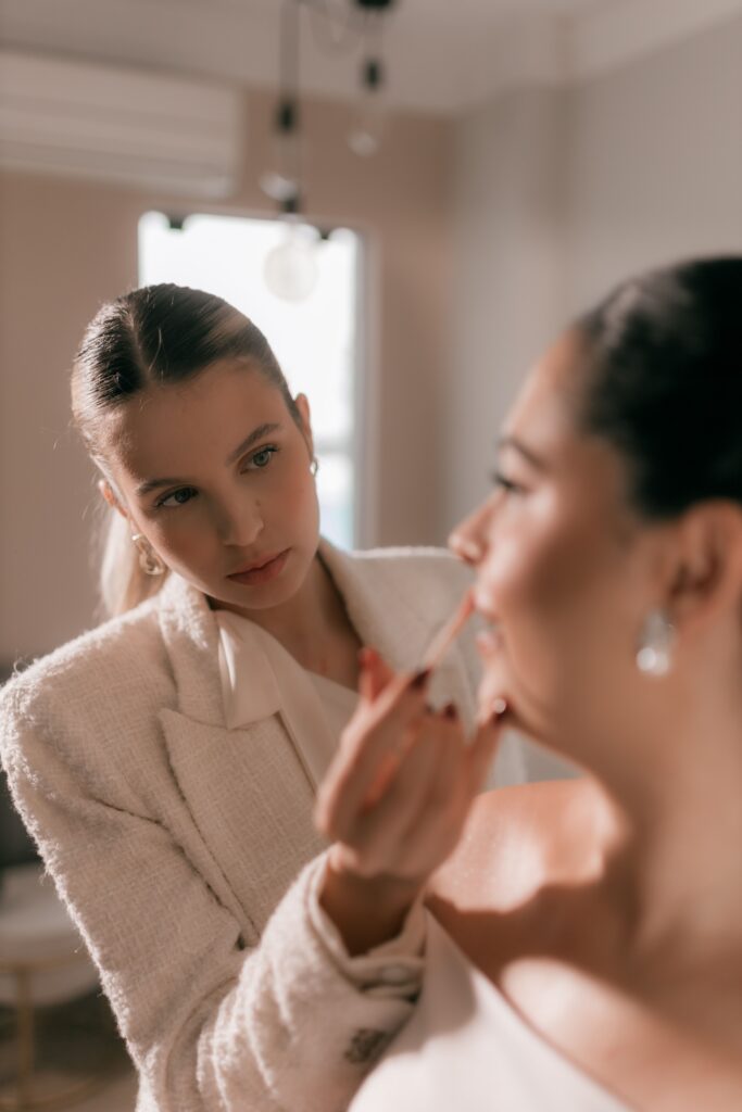Female makeup artist applying makeup to a bride.