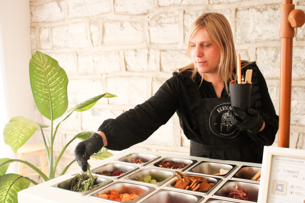 A business owner serving charcuterie from their charcuterie cart during a photoshoot in Kingston, Ontario. 