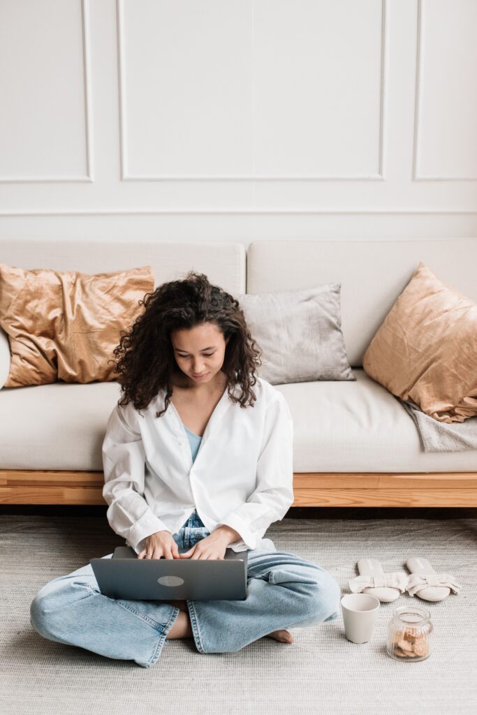 Woman working at computer on the floor in the living room. 