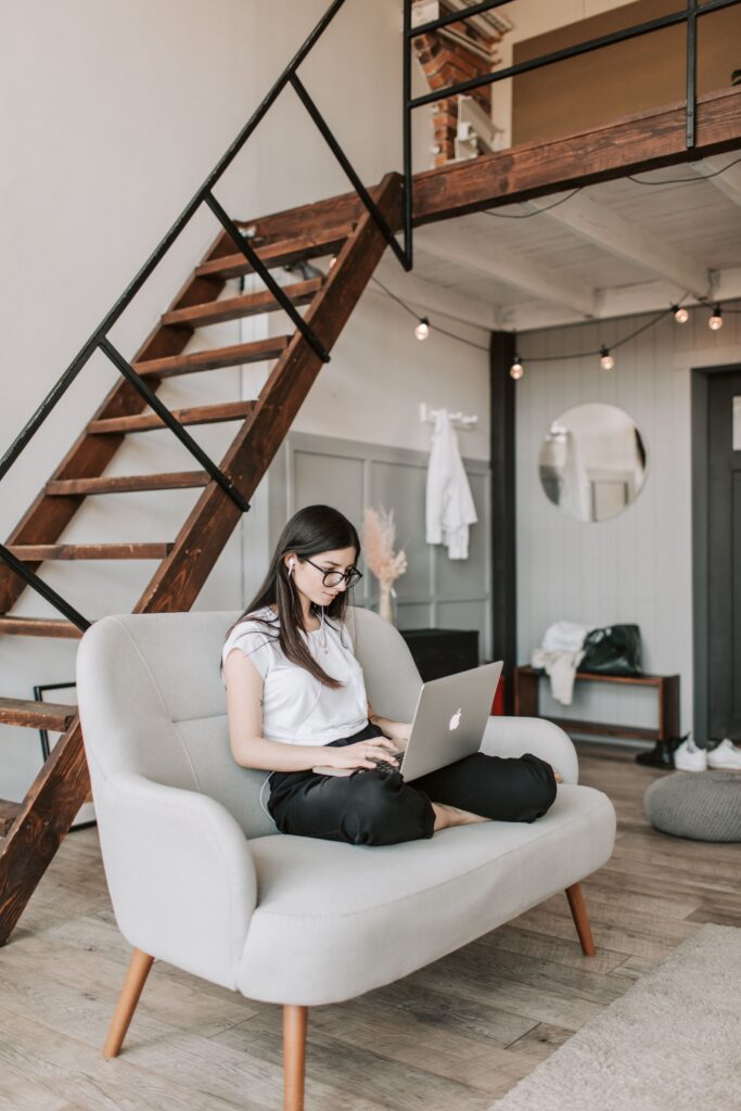 Woman sitting on her couch and working on her computer at home.