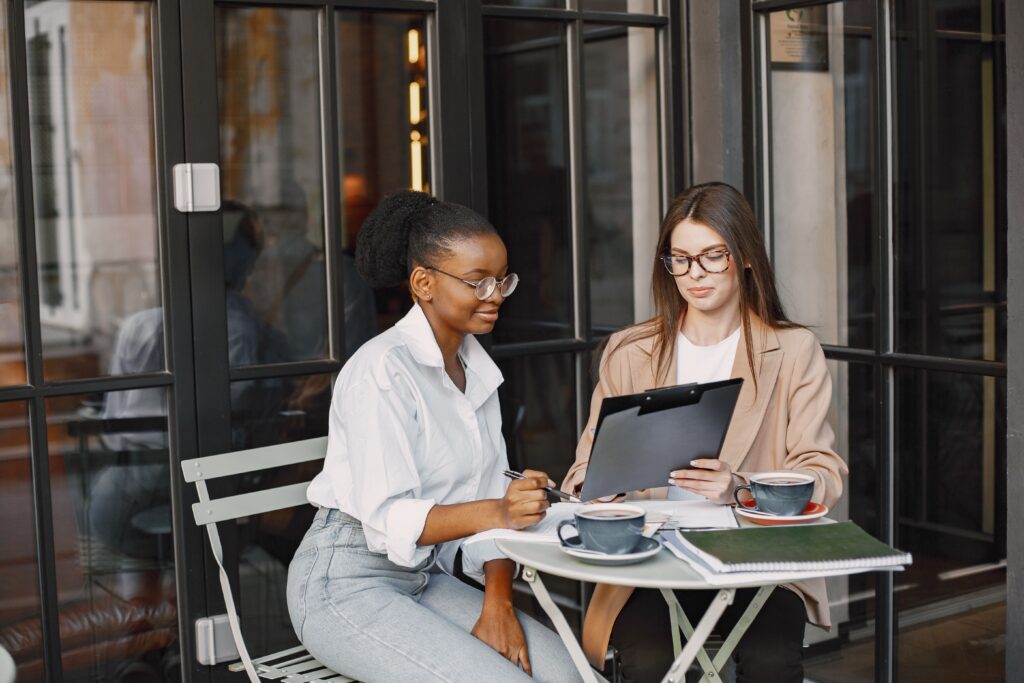 Two women meeting at coffee shop to discuss SEO structure on a website. 