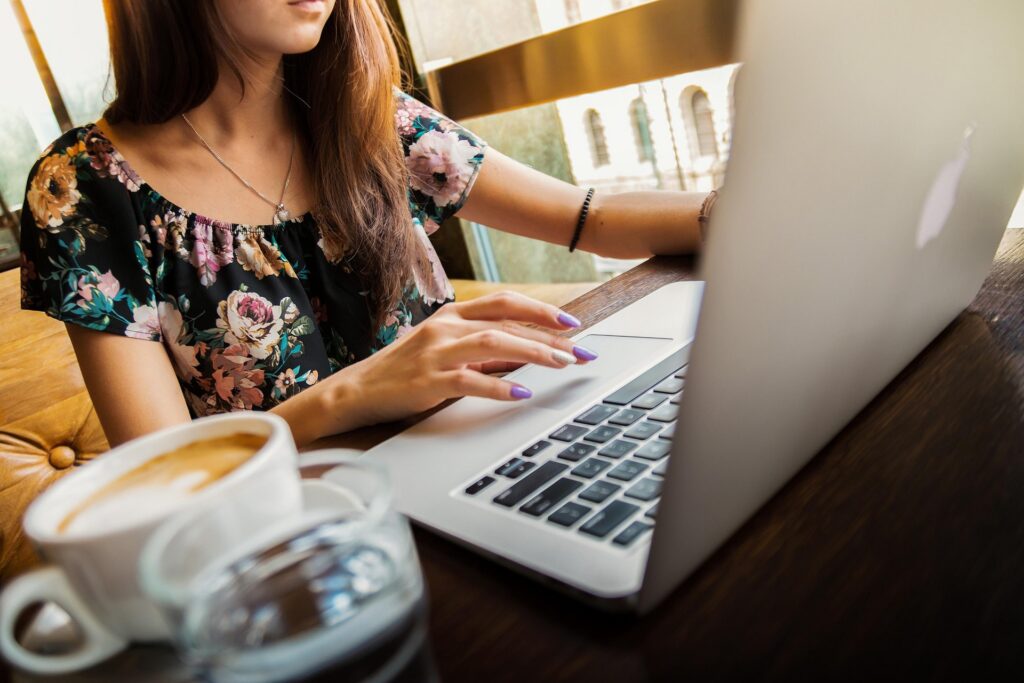 Woman sitting in a coffee shop designing a website for a client.