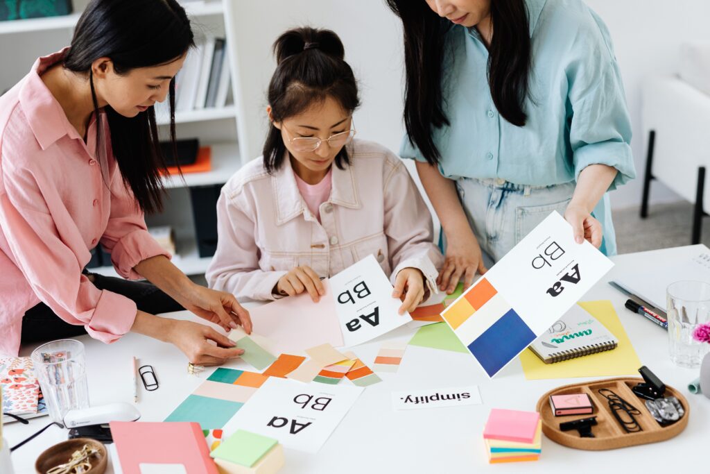 A group of women looking at visual brand elements like colour palettes and fonts.