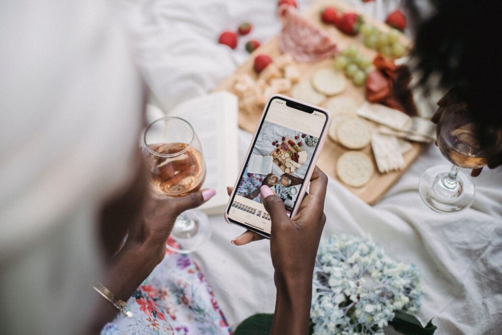 A social media manager taking pictures of a charcuterie board and a glass of wine.