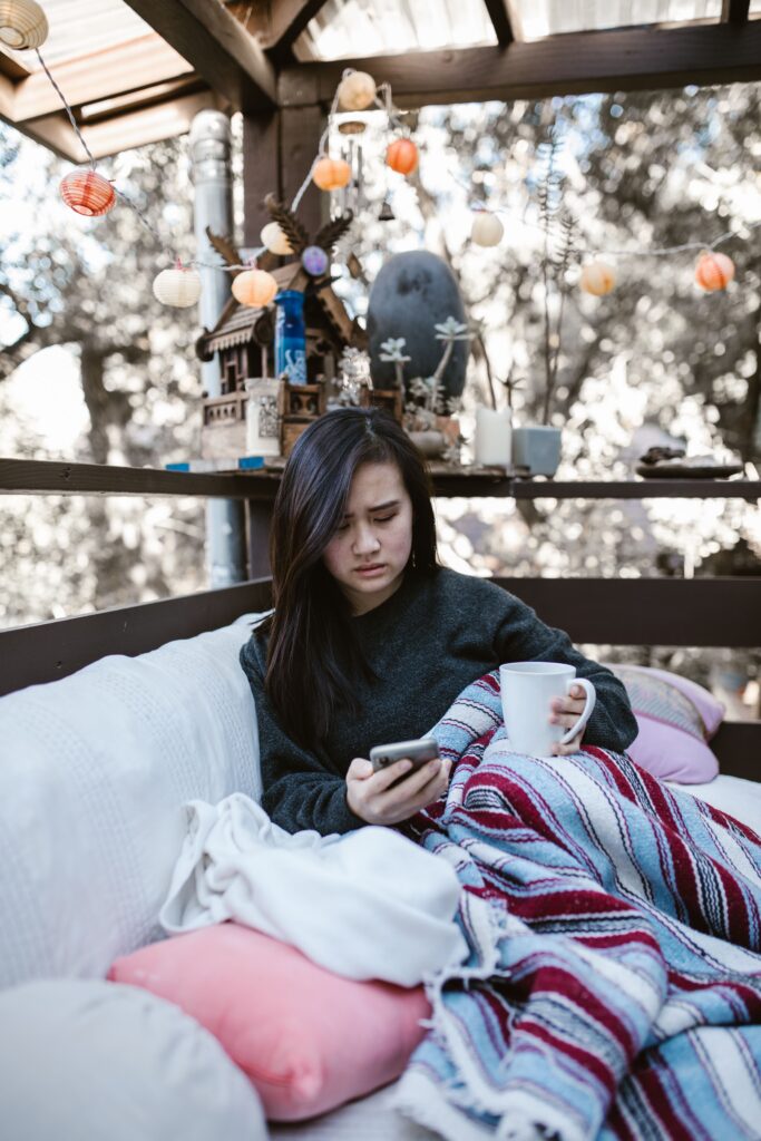 Business owner sitting on a couch with coffee looking at social media for her business.